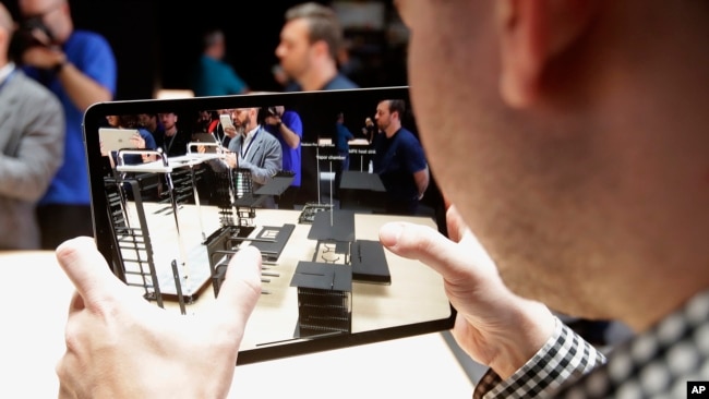 A man looks at an iPad in the display room at the Apple Worldwide Developers Conference in San Jose, Calif., Monday, June 3, 2019. (AP Photo/Jeff Chiu)