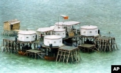 FILE - A Chinese flag and a satellite dish are prominently displayed in a structure built by China in one of the islands in the Spratly Islands.