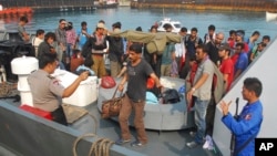 Indonesian police officers guard asylum seekers on a patrol boat upon arrival at a port in Merak, Banten province, Indonesia, Oct 12, 2012.