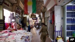 A Kurdish man wearing traditional clothes passes under a Kurdish flag in Irbil’s old bazaar, IraqThursday, Aug. 24, 2017. Despite calls from Baghdad and the United States to postpone the vote, Iraq’s semi-autonomous Kurdish region is pressing ahead with plans to hold a referendum on independence September 25. 