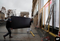 Workers carry a wooden piece to protect shop windows on the Champs-Elysees avenue, Dec. 7, 2018 in Paris.