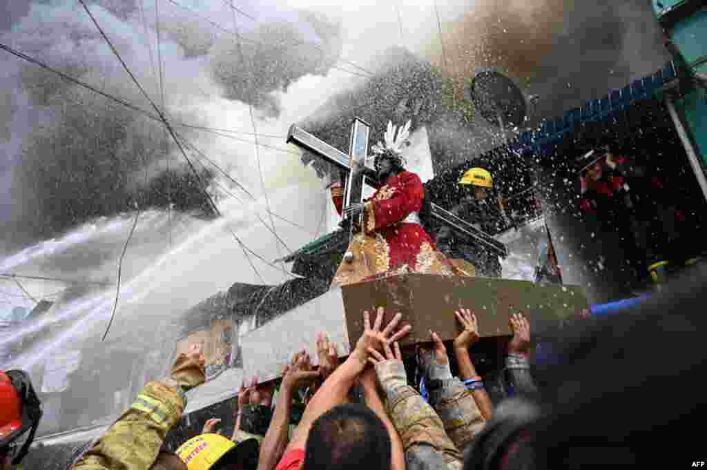 Residents and firefighters carry a Black Nazarene statue from a burning house after a fire broke out at an unofficial settlement in Manila, Philippines.