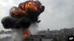 In this image made from amateur video released by the Shaam News Network and accessed Sunday, April 15, 2012, smoke billows an impact following purported shelling in Homs, Syria. 