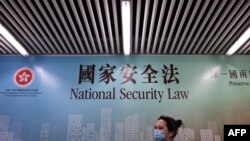 行人走过香港街头港版国安法的宣传牌。（2020年7月28日）