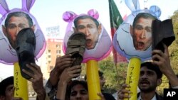 FILE - Pakistani protesters hold up shoes and caracatures of U.S. President George W. Bush during a demonstration in support of Iraqi journalist Muntadhar al-Zeidi in Lahore, Pakistan, Dec. 21, 2008. 