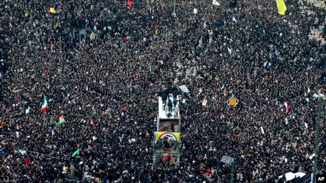 1月5日，在伊朗的瑪瑟赫德市，蘇萊曼尼和其他人的棺材被抬上了卡車。周圍是悼念的人群。
