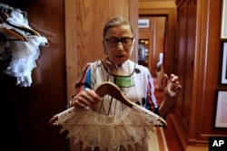 U.S. Supreme Court Justice Ruth Bader Ginsburg shows the many different collars (jabots) she wears with her robes, in her chambers, at the Supreme Court building in Washington, U.S. June 17, 2016.