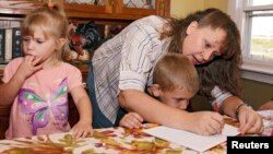 FILE - A mother works with her children during a homeschool assignment in St. Charles, Iowa, Sept. 30, 2011.