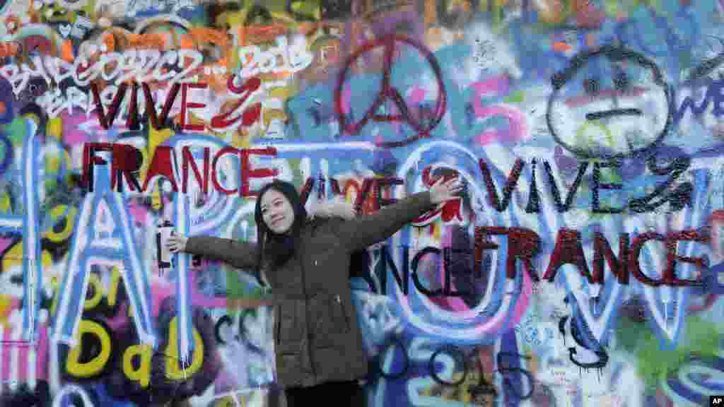 Un touriste devant le "Mur de Lennon" peint avec des massages en mémoire des victimes des attaques à Paris, à Prague, République tchèque, 16 novembre 2015. 