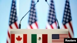 FILE - The flags of Canada, Mexico and the U.S. are seen on a lectern before a joint news conference on the closing of the seventh round of NAFTA talks in Mexico City, Mexico, March 5, 2018. U.S. President Donald is now looking to pursue separate deals with the two neighbors, a White House adviser said.