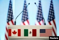FILE - The flags of Canada, Mexico and the U.S. are seen on a lectern before a joint news conference on the closing of the seventh round of NAFTA talks in Mexico City, Mexico, March 5, 2018.
