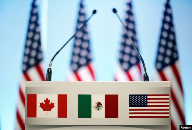 FILE - The flags of Canada, Mexico and the U.S. are seen on a lectern before a joint news conference on the closing of the seventh round of NAFTA talks in Mexico City, Mexico, March 5, 2018.