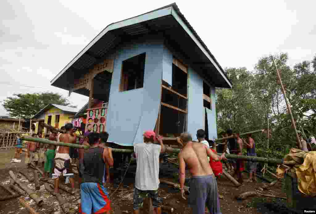 Residents lift a house damaged by Typhoon Rammasun in Batangas city, south of Manila, July 17, 2014.