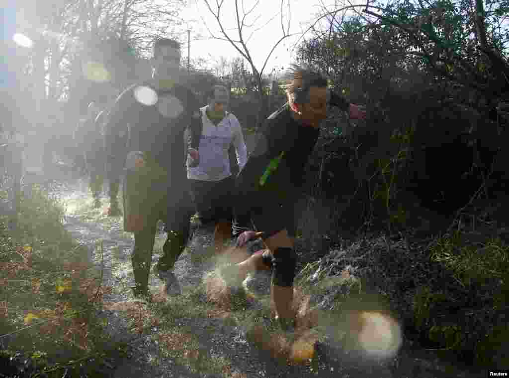 Prime Minister David Cameron reacts as he competes in the Great Brook Run, a mile long course through water and mud, at Chadlington in southern England.