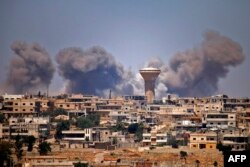 FILE - Smoke rises above rebel-held areas of the city of Daraa during reported airstrikes by Syrian regime forces, July 5, 2018.