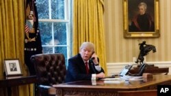 President Donald Trump speaks on the phone with King of Saudi Arabia Salman bin Abd al-Aziz Al Saud in the Oval Office at the White House in Washington, Sunday, Jan. 29, 2017. (AP Photo/Manuel Balce Ceneta)