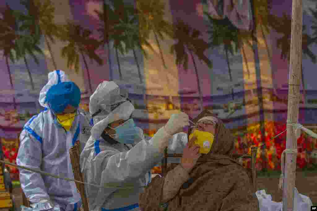 A health worker takes a nasal swab sample of a Kashmiri woman to test for COVID-19 in Srinagar, Indian-controlled Kashmir. India&#39;s total COVID-19 positive cases exceed 9.7 million, the second highest behind the United States.