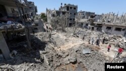 Palestinians gather at the site of destroyed houses in the aftermath of Israeli air and artillery strikes as cross-border violence between the Israeli military and Palestinian militants continues, in the northern Gaza Strip, May 14, 2021. 