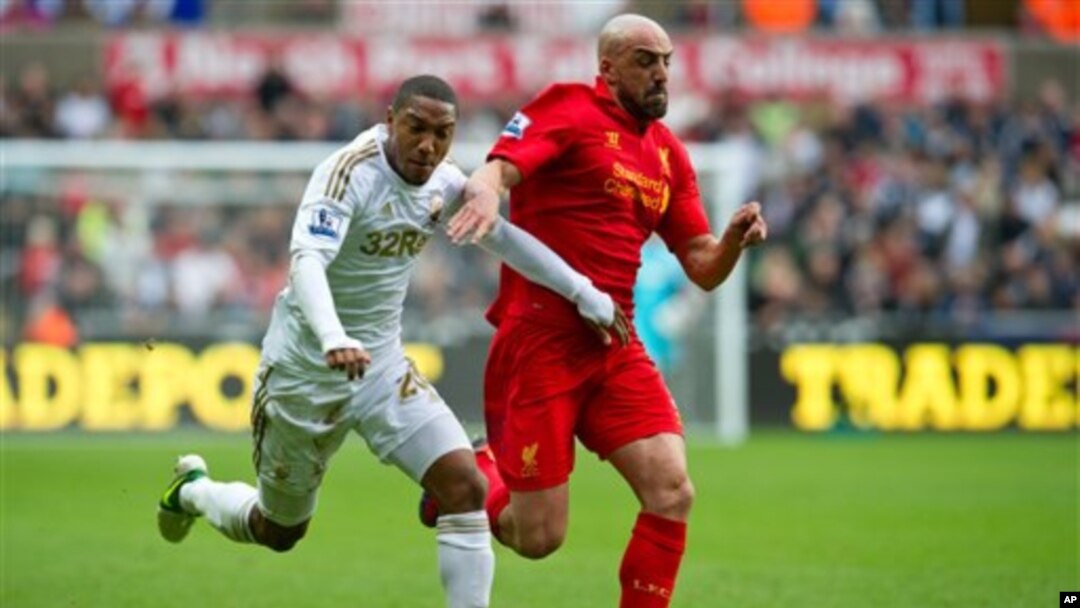 Jonathan de Guzman, kiri, dari Klub Swansea berusaha merebut bola dari Jose Enrique dari klub Liverpool dalam pertandingan Liga Premier hari Minggu (25/11).
