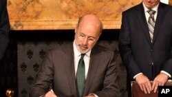 Pennsylvania Gov. Tom Wolf signs an executive order for his administration to start working on regulations to bring Pennsylvania into a nine-state consortium that sets a price and limits on greenhouse gas emissions from power plants, Oct. 3, 2019.