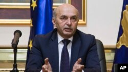 Isa Mustafa of the Democratic League of Kosovo speaks to reporters after signing a coalition agreement with the Democratic Party of Kosovo to form the next government in Pristina, Dec. 8, 2014.