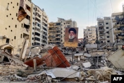 Potret pemimpin Hizbullah yang terbunuh, Hassan Nasrallah, terlihat di antara puing-puing di lingkungan Rouweiss, pinggiran selatan Beirut, pada 10 Oktober 2024. (Foto: AFP)