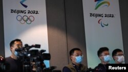 Reporters are seen in front of the Beijing 2022 Winter Olympic and Paralympic Games signs during a news conference on the construction progress of the sports event venues, at the headquarters of the Beijing Organising Committee, in Beijing, China July 30…