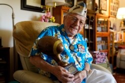 Mickey Ganitch, a 101-year-old survivor of the attack on Pearl Harbor, holds a football statue he was given, in the living room of his home in San Leandro, Calif., Nov. 20, 2020.
