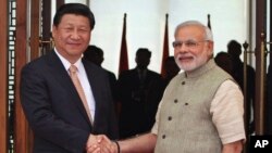 FILE - Indian Prime Minister Narendra Modi, right, shakes hand with Chinese President Xi Jinping as he welcomes him at a hotel in Ahmadabad, India, Sept. 7, 2014. The two leaders will meet April 27-28, 2018, for a visit that some experts have described as a possible way to reset a complicated relationship between the two Asian powers.
