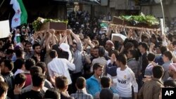 In this Saturday, April 21, 2012 photo, Syrians carry the bodies of an infant, Adam al Najjar, and Free Syrian Army fighter, Mowaffaq al Nablsi, 42, during their funeral in Douma, a suburb of Damascus, Syria.