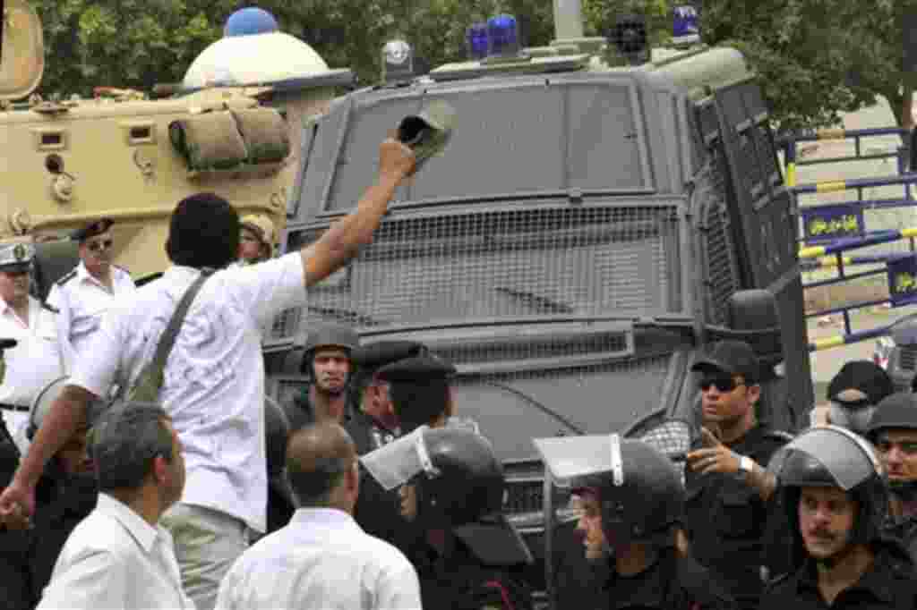 A protester with writing on his shirt in arabic reading "Execution, execution, for the killer of the youth" holds up his shoe as a gesture of contempt at a police van believed by protesters to be transporting former Egyptian Interior Minister Habib al-Adl