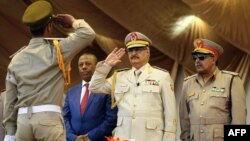 Le maréchal Khalifa Haftar, au centre, salue le chef d'état-major de l'armée nationale libyenne Abdelrazak al-Nadhuri, à droite, et l'ancien Premier ministre libyen Abdullah al-Thani, chef du gouvernement à Bayda, lors d’une parade militaire à Benghazi, Libye, le 7 mai 2018. 