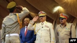 Le maréchal Khalifa Haftar, au centre, salue le chef d'état-major de l'armée nationale libyenne Abdelrazak al-Nadhuri, à droite, et l'ancien Premier ministre libyen Abdullah al-Thani, chef du gouvernement à Bayda, lors d’une parade militaire à Benghazi, le 7 mai 2018