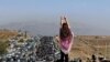 FILE - This UGC image posted on Twitter reportedly on Oct. 26, 2022 shows an unveiled woman standing atop a vehicle as thousands make their way towards a cemetery near Mahsa Amini's hometown to mark 40 days since her death.