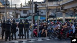 Police standing guard as commuters on motorbikes stop at a traffic signal near the venue of the upcoming Asia-Pacific Economic Cooperation (APEC) forum in Bangkok, Thailand, Nov. 15, 2022.