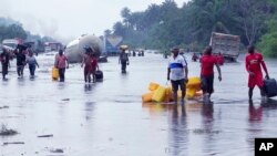 FILE- People wade through flooded roads in Bayelsa, Nigeria, Oct. 20, 2022. Climate change is to blame for the deadliest yet heavy rains and flooding that swamped Nigeria between the months of June and October.