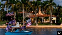 A boat with supporters flying flags for former President Donald Trump is anchored outside of his club, Mar-a-lago in Palm Beach, Nov. 15, 2022. 