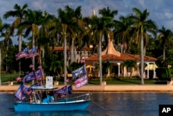 A boat with supporters flying flags for former President Donald Trump is anchored outside of his club, Mar-a-lago in Palm Beach, Nov. 15, 2022.