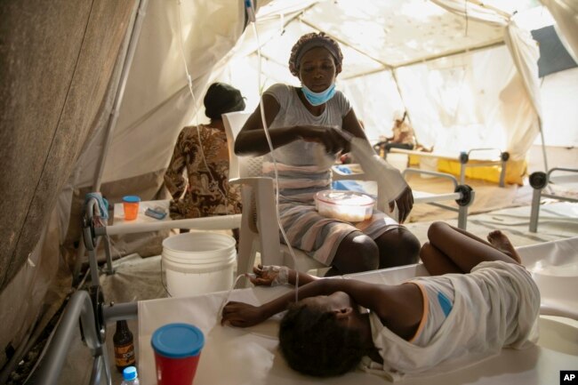 A woman uses a towel to swat flies away from her daughter stricken with cholera, at a clinic run by Doctors Without Borders in Port-au-Prince, Haiti, Friday, Nov. 11, 2022. (AP Photo/Odelyn Joseph)