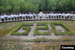 Presiden Joko Widodo bersama pimpinan G20 dan pimpinan organisasi internasional mengangkat cangkul usai melakukan penanaman mangrove pada acara KTT G20 di Taman Hutan Raya Ngurah Rai, Denpasar, Bali, 16 November 2022. (Foto: Akbar Nugroho Gumay/G20 Media Center via REUTERS)