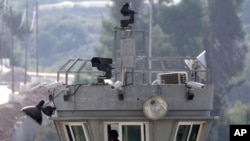 Two robotic guns sit atop a guard tower with surveillance cameras pointed at the Aroub refugee camp in the West Bank, Thursday, Oct. 6, 2022. (AP Photo/Mahmoud Illean)