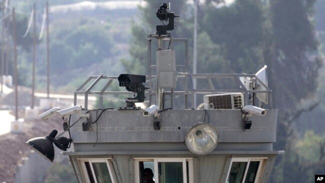 Two robotic guns sit atop a guard tower with surveillance cameras pointed at the Aroub refugee camp in the West Bank, Thursday, Oct. 6, 2022. (AP Photo/Mahmoud Illean)