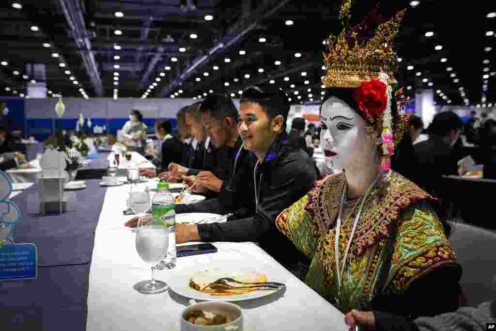 A Thai traditional dancer in costume finishes her lunch at the Asia-Pacific Economic Cooperation APEC summit, in Bangkok, Thailand.