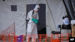 FILE - A medical worker disinfects a tent used for suspected Ebola victims inside the Ebola isolation center of Madudu Health Center III, in the village of Madudu, in the Mubende district of Uganda, Nov. 1, 2022. 