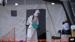 FILE - A medical worker disinfects a tent used for suspected Ebola victims inside the Ebola isolation center of Madudu Health Center III, in the village of Madudu, in the Mubende district of Uganda, Nov. 1, 2022. 