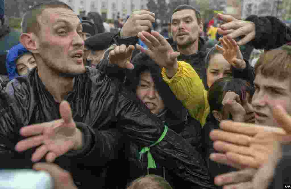 Local residents rush for an aid supply distribution in the center in Kherson, Ukraine.