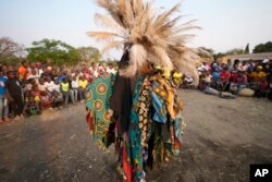 Los miembros de la sociedad secreta de baile Gule Wamkulu con máscaras sangrientas y trajes coloridos realizan su danza ritual en Harare, Zimbabue, el 23 de octubre de 2022.