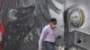 Un peatón que usa una máscara facial protectora como precaución contra la propagación del nuevo coronavirus, pasa junto a un mural con una rata gigante, en Quito, Ecuador, el miércoles 3 de junio de 2020.