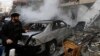 A Lebanese man walks past a damaged car at the site of an explosion in a stronghold of the Shiite Hezbollah group at the southern suburb of Beirut, Jan. 2, 2014. 