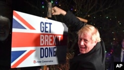 Britain's Prime Minister and Conservative party leader Boris Johnson poses as he hammers a "Get Brexit Done" sign into the garden of a supporter, in Benfleet, east of London on Dec. 11, 2019, the final day of campaigning for the general election. 